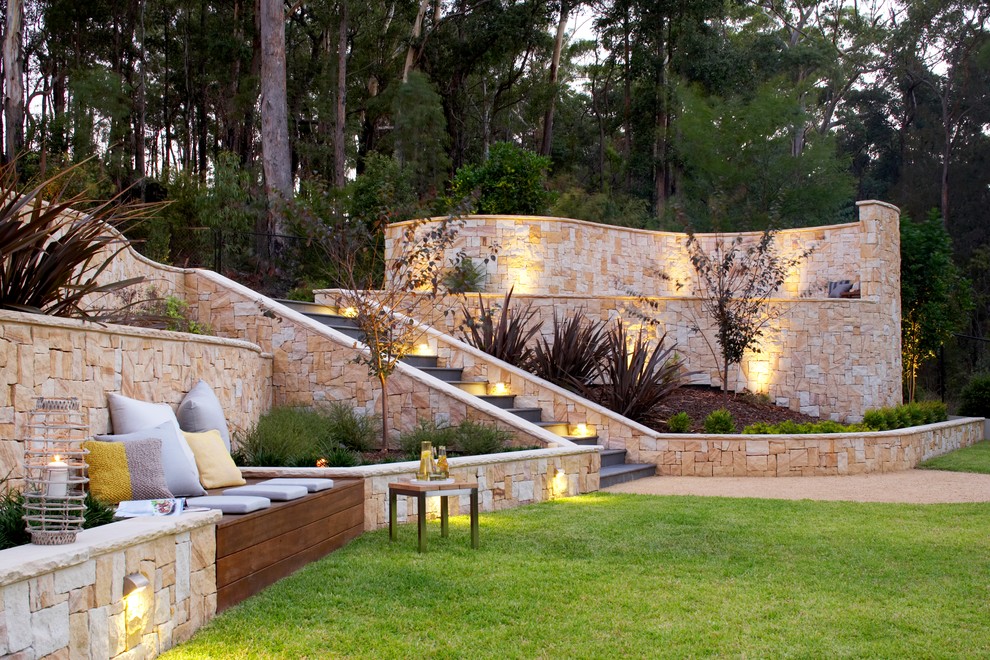 Imagen de jardín actual grande en patio trasero con muro de contención y adoquines de piedra natural