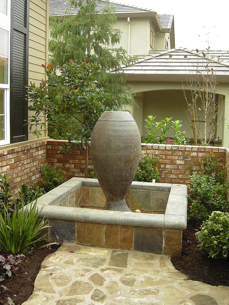 This is an example of a mid-sized eclectic full sun backyard stone landscaping in Sacramento for summer.