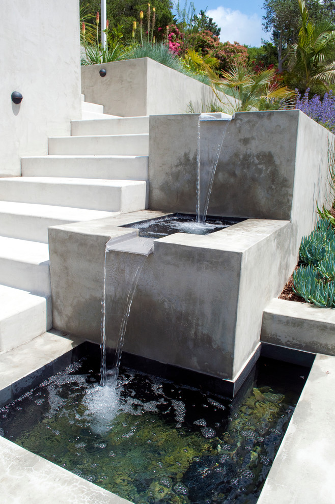 Inspiration för moderna trädgårdar i full sol längs med huset, med en fontän