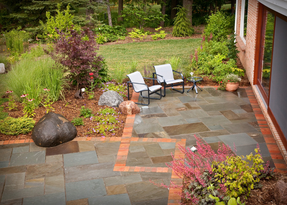 Photo of a mid-sized contemporary full sun backyard stone landscaping in Milwaukee for summer.