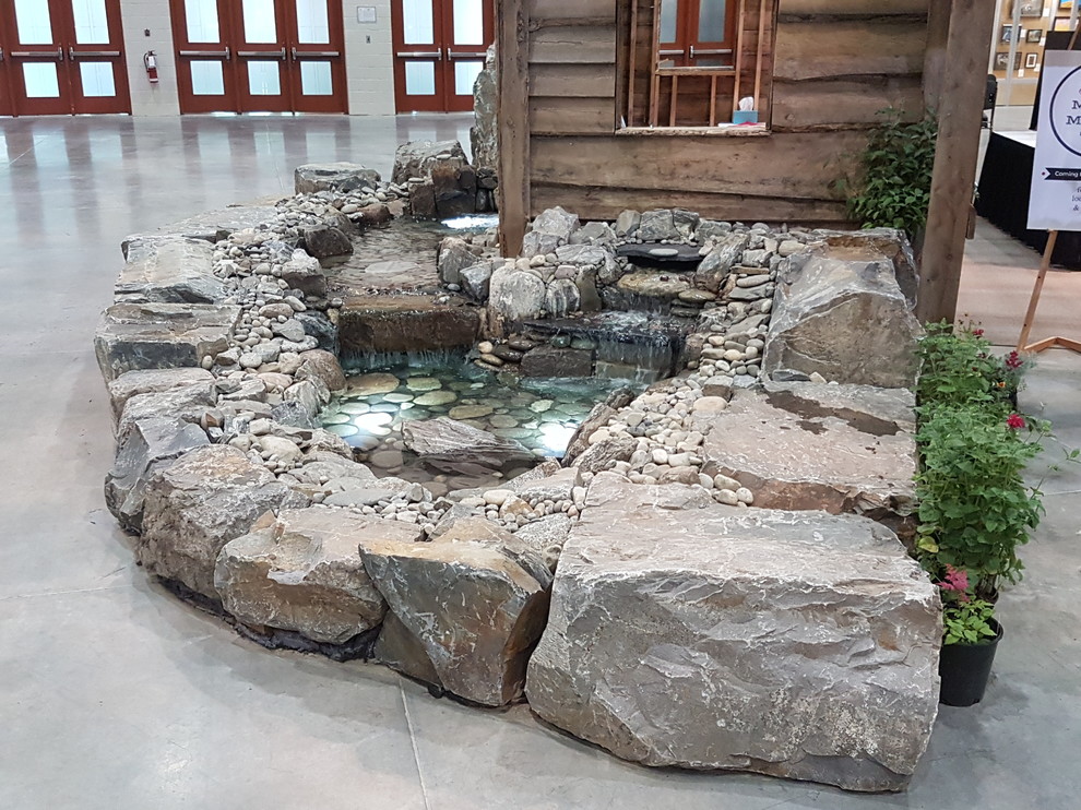 Photo of a medium sized traditional back partial sun garden in Calgary with a water feature and natural stone paving.