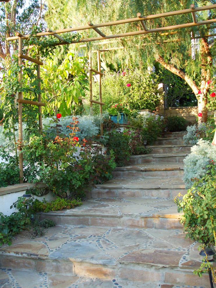 Exempel på en medelhavsstil trädgård i slänt, med naturstensplattor