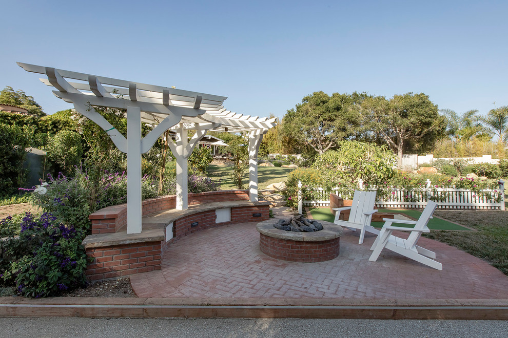 This is an example of a coastal back partial sun garden in Santa Barbara with an outdoor sport court, a fire feature and brick paving.