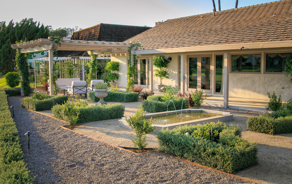 На фото: солнечный регулярный сад среднего размера на заднем дворе в средиземноморском стиле с хорошей освещенностью, мощением клинкерной брусчаткой, водопадом и с металлическим забором с