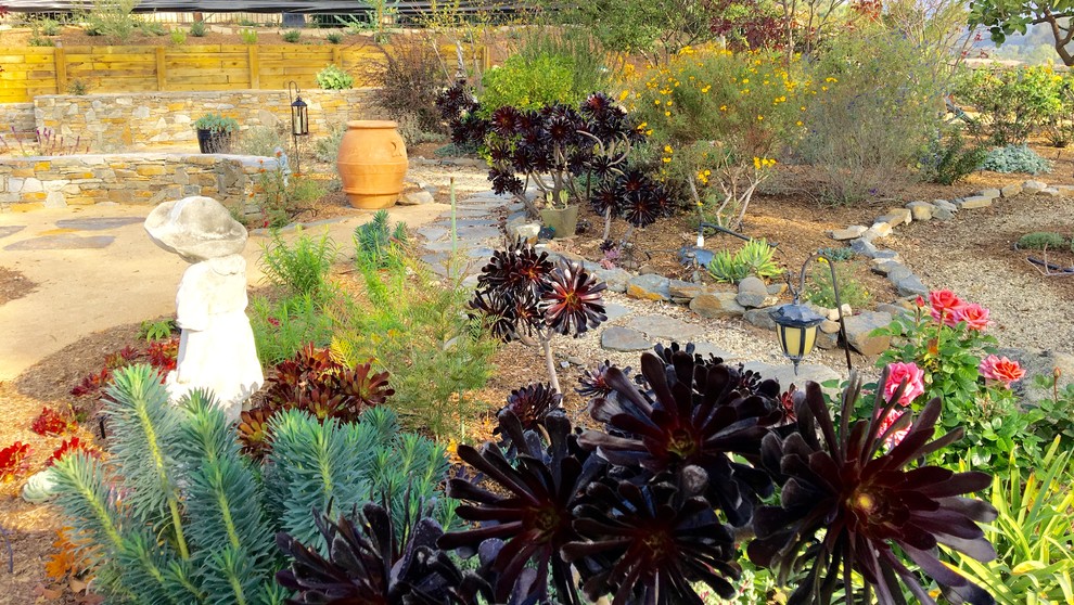 Foto på en stor medelhavsstil bakgård i full sol som tål torka, med en stödmur och naturstensplattor