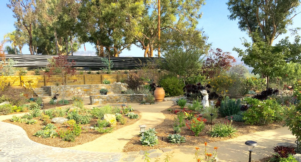 Esempio di un grande giardino xeriscape mediterraneo esposto in pieno sole dietro casa con un muro di contenimento e pavimentazioni in pietra naturale