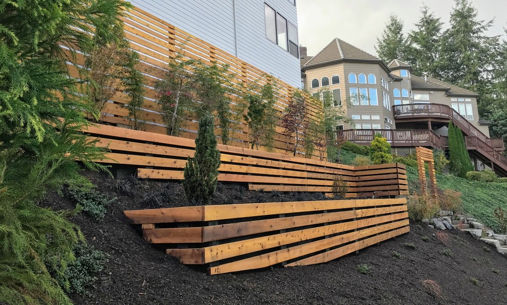 Photo of a medium sized modern sloped partial sun garden in Portland with a retaining wall.