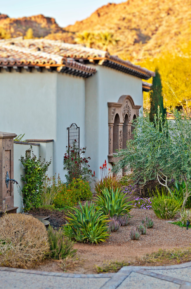 Photo of a large mediterranean partial sun front yard stone landscaping in Phoenix.