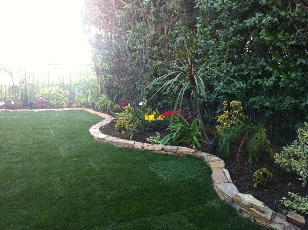 Photo of a mid-sized traditional partial sun backyard stone landscaping in Los Angeles.