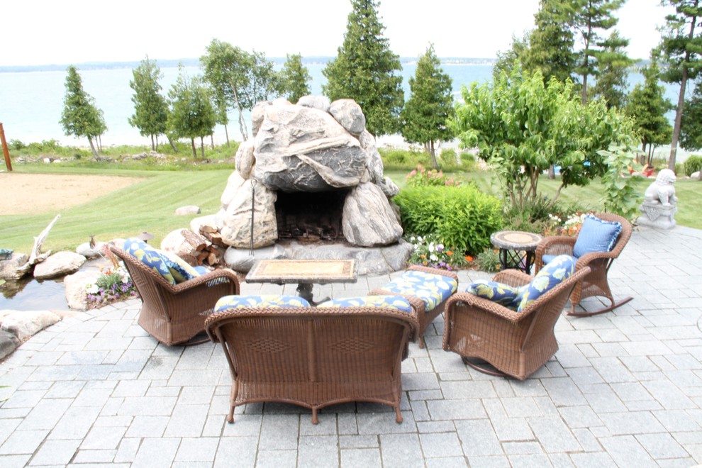 Diseño de patio tropical grande en patio trasero con brasero y adoquines de piedra natural