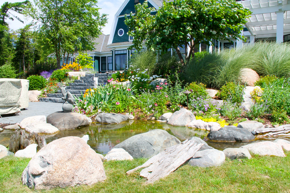 Modelo de jardín exótico grande en patio trasero con estanque, exposición total al sol y adoquines de piedra natural