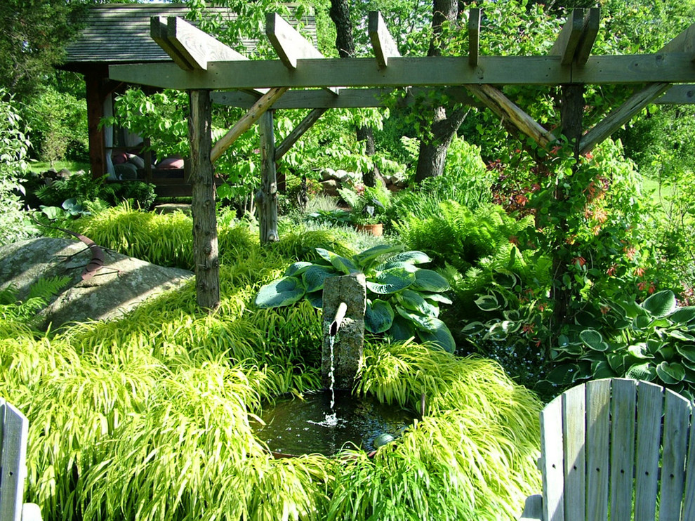 Diseño de jardín de estilo de casa de campo en patio trasero con jardín francés, exposición reducida al sol y adoquines de piedra natural