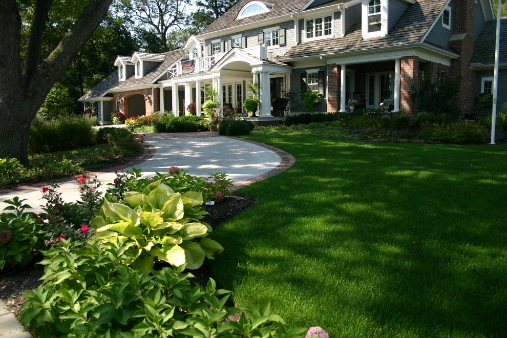 Exempel på en mycket stor klassisk uppfart i delvis sol framför huset på sommaren, med marksten i tegel och en trädgårdsgång