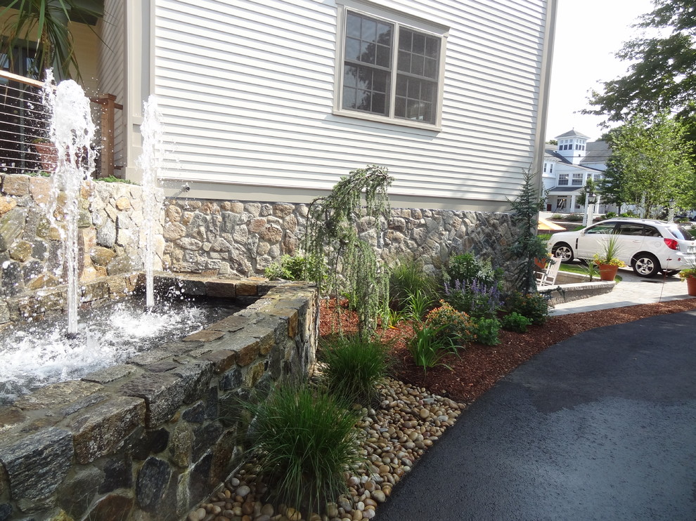 This is an example of a mid-sized rustic partial sun courtyard stone retaining wall landscape in Boston for summer.