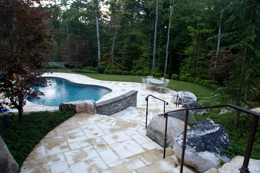 Photo of a large traditional full sun backyard concrete paver retaining wall landscape in DC Metro.