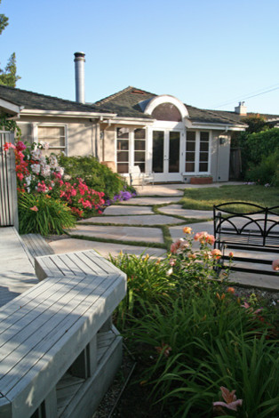 Exempel på en liten klassisk trädgård i delvis sol på sommaren, med en trädgårdsgång och trädäck