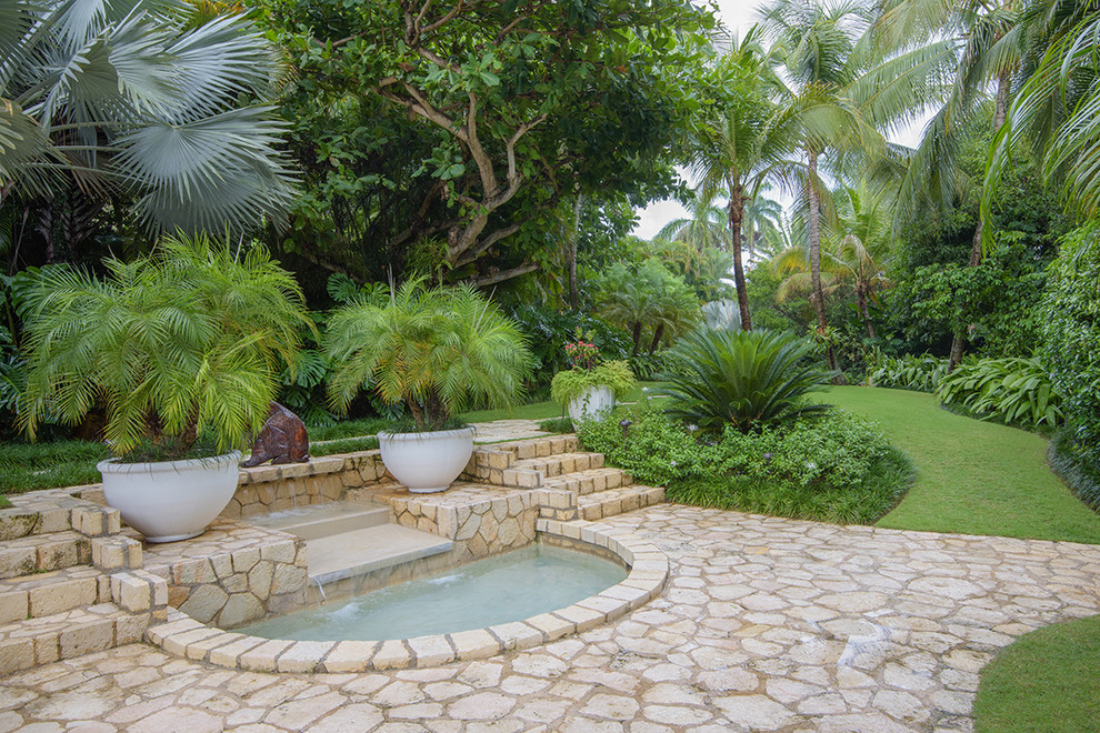 Immagine di un ampio giardino tropicale con pavimentazioni in pietra naturale