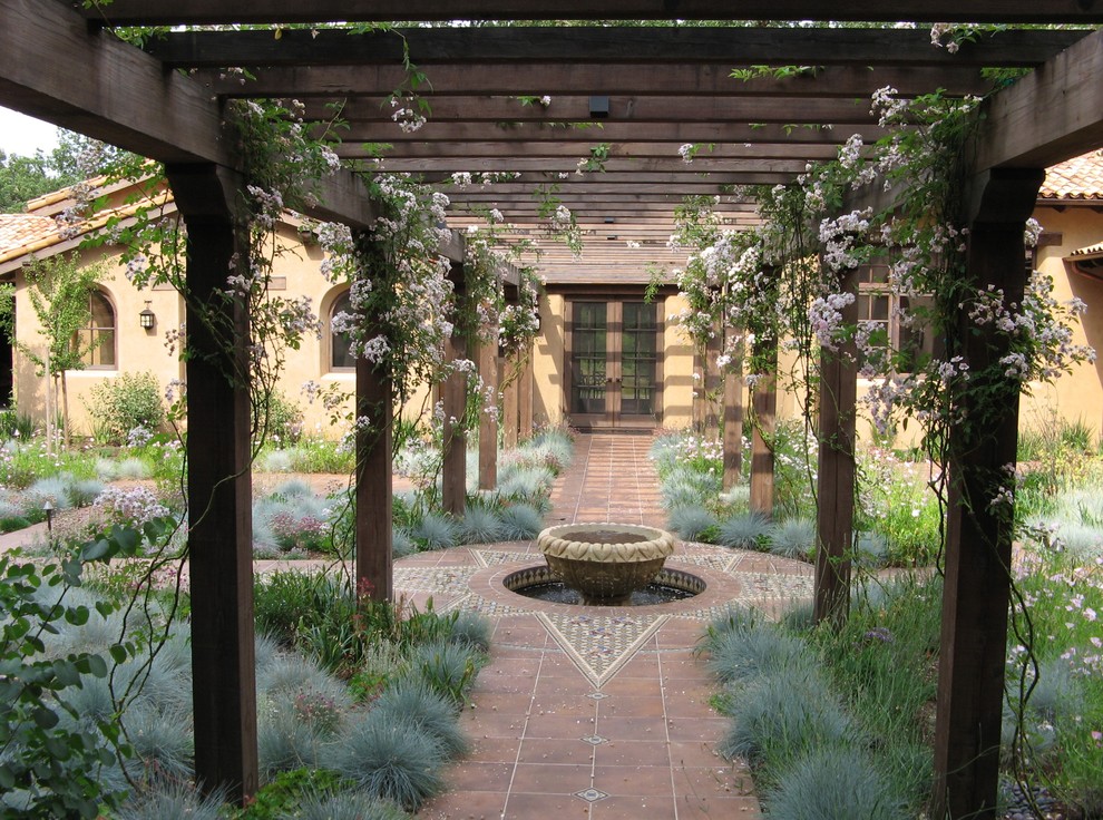 This is an example of a medium sized mediterranean courtyard garden in Denver with a water feature.
