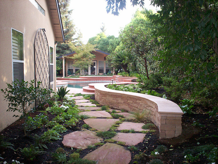 На фото: большой тенистый регулярный сад на заднем дворе в классическом стиле с садовой дорожкой или калиткой и покрытием из каменной брусчатки