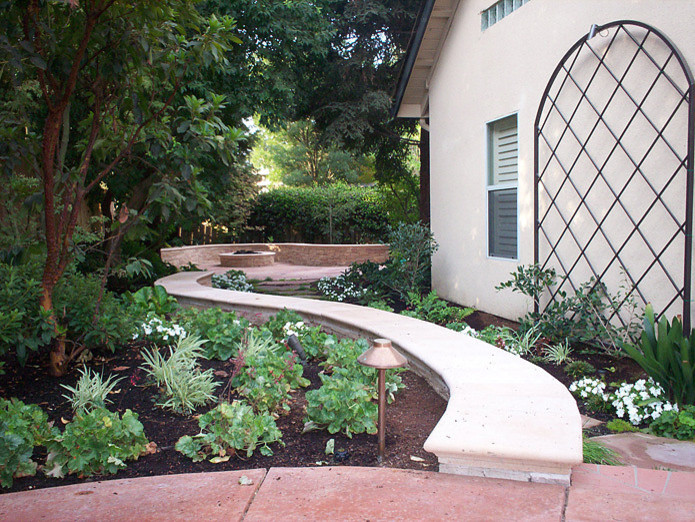 Diseño de jardín tradicional de tamaño medio en primavera en patio lateral con jardín francés, brasero, exposición total al sol y adoquines de piedra natural
