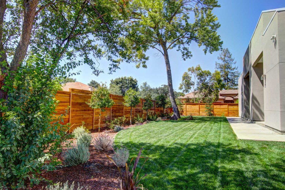Photo of an expansive modern back partial sun garden in Sacramento with a fireplace and concrete paving.