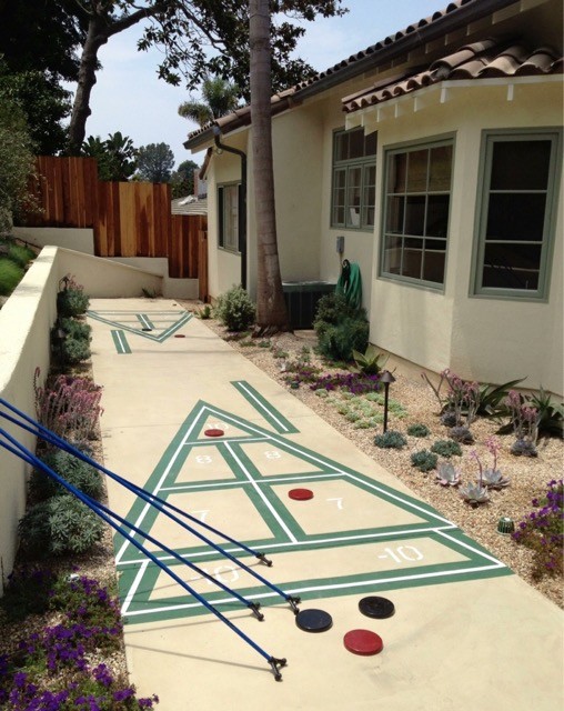 This is an example of a medium sized mediterranean back xeriscape full sun garden in Los Angeles with a retaining wall and concrete paving.