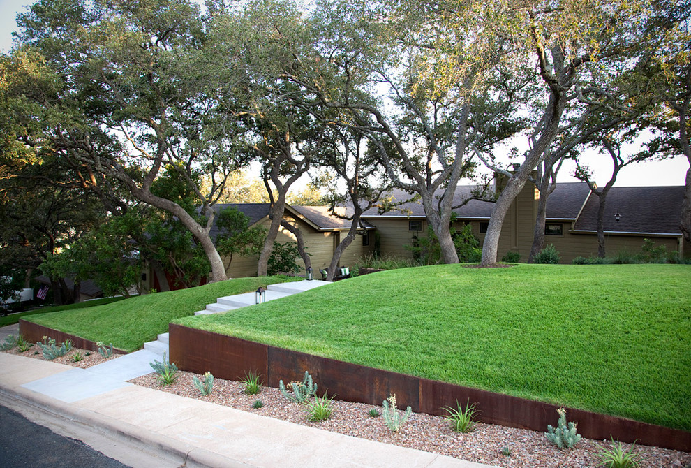 This is an example of a medium sized modern front xeriscape garden in Austin with concrete paving and lawn edging.