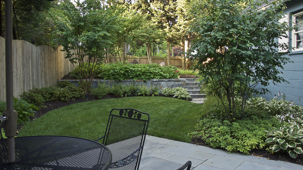 Small traditional sloped partial sun garden for summer in DC Metro with natural stone paving and a retaining wall.