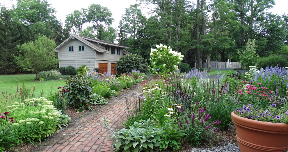 Exempel på en liten amerikansk uppfart i delvis sol framför huset på sommaren, med en trädgårdsgång och marksten i tegel