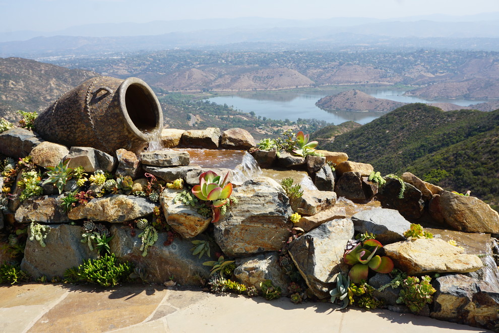 Mediterraner Garten hinter dem Haus mit Wasserspiel, direkter Sonneneinstrahlung und Natursteinplatten in San Diego