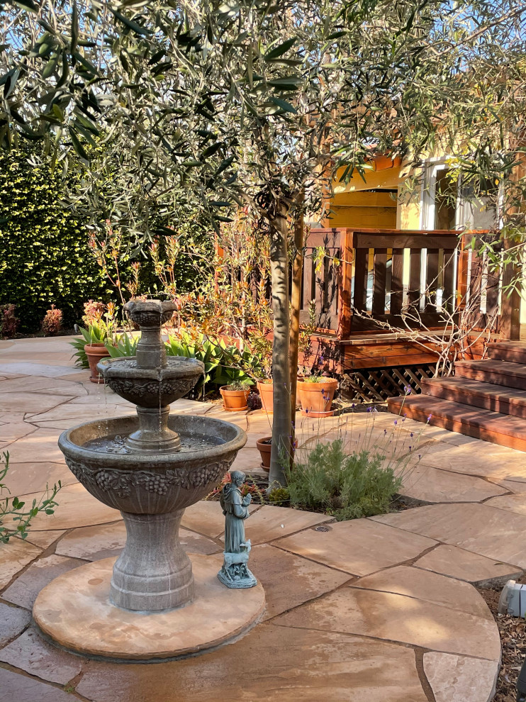 Esempio di un giardino xeriscape mediterraneo esposto in pieno sole di medie dimensioni e dietro casa in primavera con un focolare, pavimentazioni in mattoni e recinzione in legno