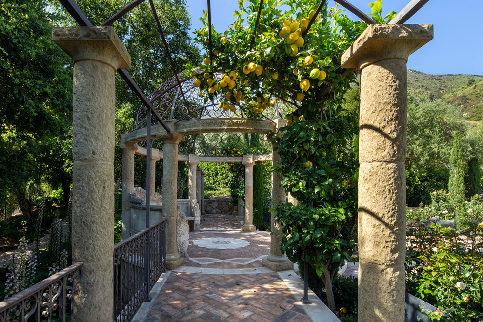 Immagine di un ampio giardino formale mediterraneo esposto in pieno sole nel cortile laterale con fontane e pavimentazioni in pietra naturale