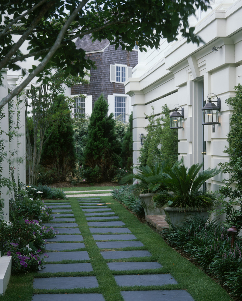 Exempel på en klassisk trädgård framför huset, med naturstensplattor
