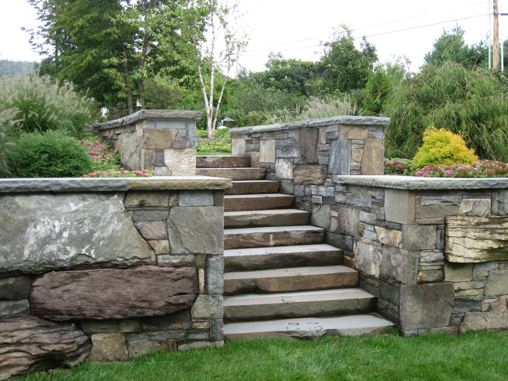 Photo of an expansive rustic back full sun garden for summer in Burlington with a retaining wall and natural stone paving.