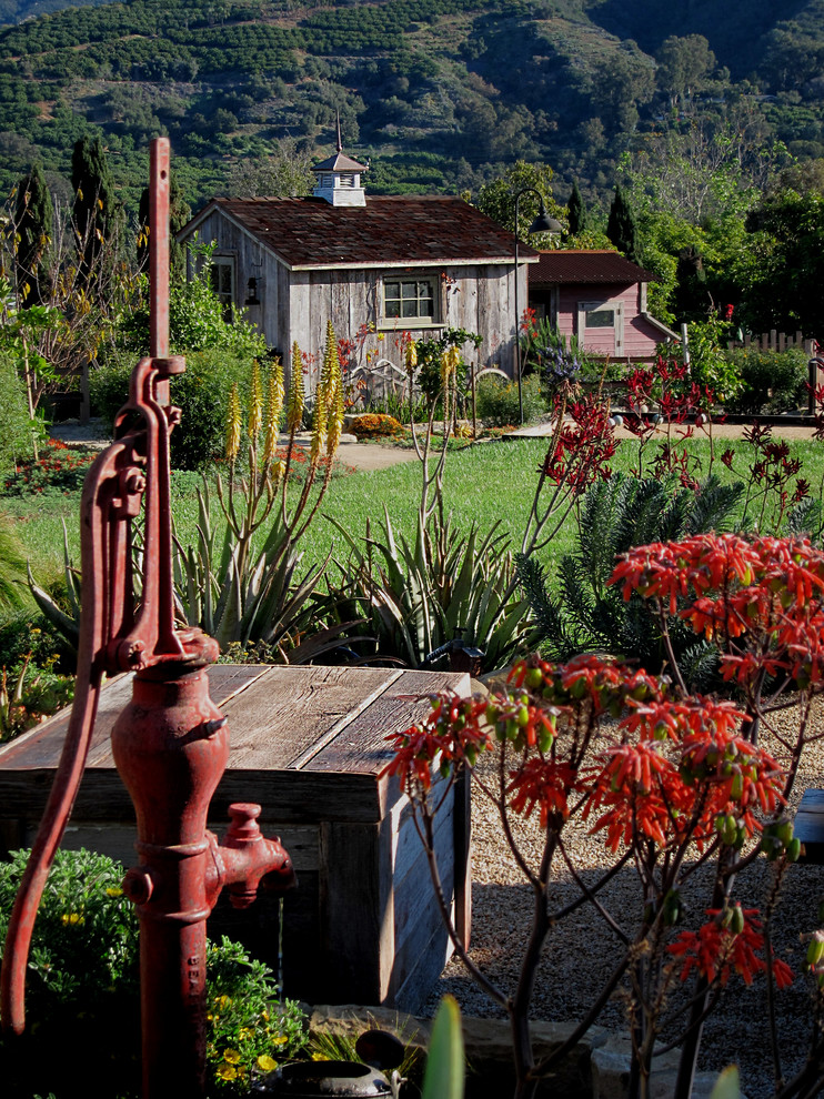 Immagine di un piccolo giardino country esposto in pieno sole dietro casa in estate con fontane e ghiaia