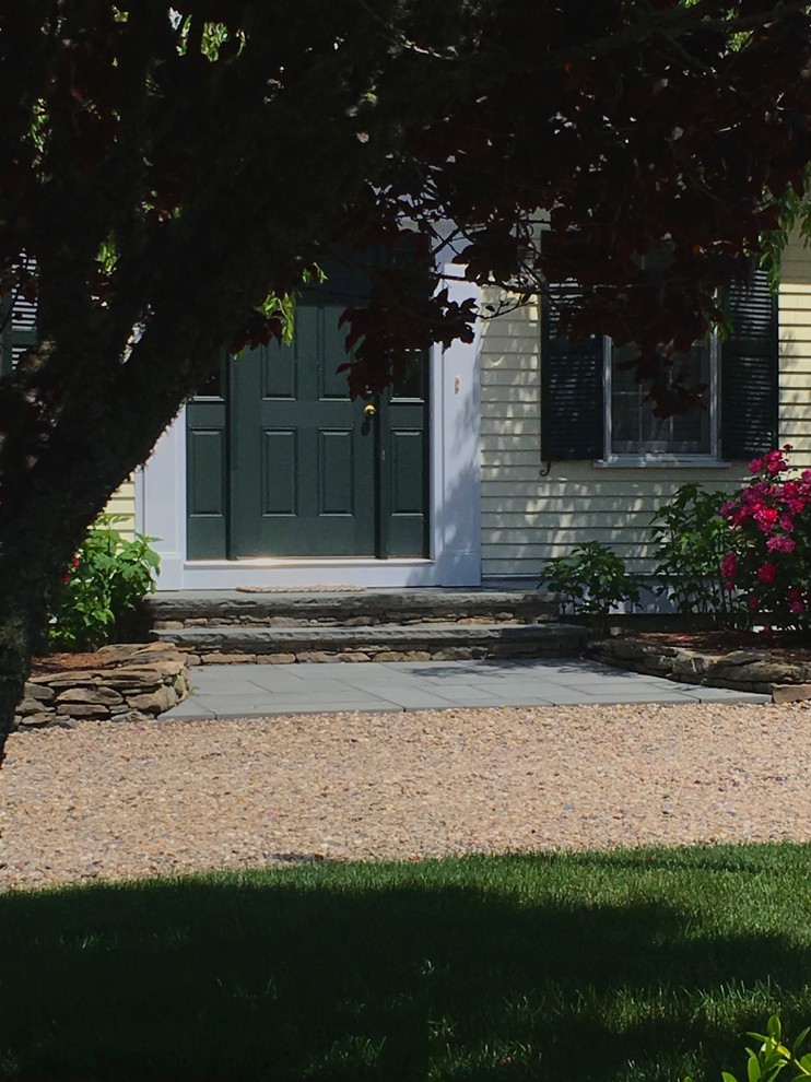 Immagine di un grande vialetto d'ingresso minimal davanti casa con un muro di contenimento e pavimentazioni in pietra naturale