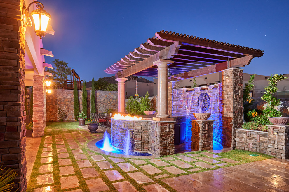 Immagine di un giardino formale mediterraneo dietro casa con un focolare e pavimentazioni in pietra naturale