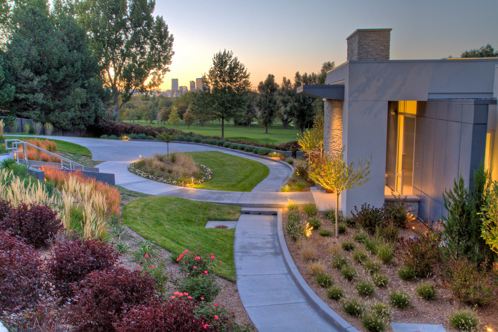 This is an example of a large contemporary front formal partial sun garden steps in Denver with concrete paving.