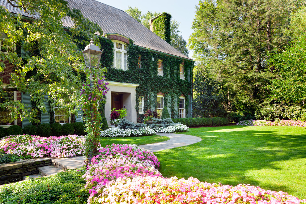 На фото: большой участок и сад на переднем дворе в классическом стиле с полуденной тенью, мощением тротуарной плиткой и клумбами