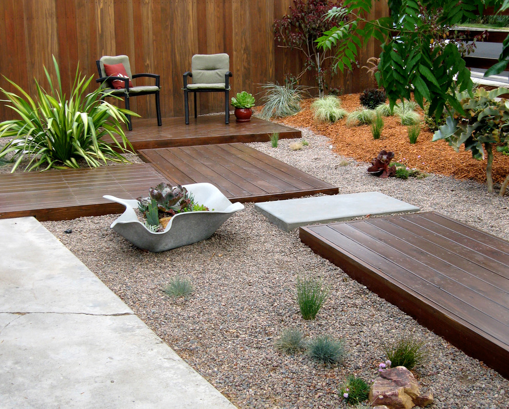 На фото: маленький солнечный засухоустойчивый сад на переднем дворе в современном стиле с садовой дорожкой или калиткой, хорошей освещенностью и настилом для на участке и в саду