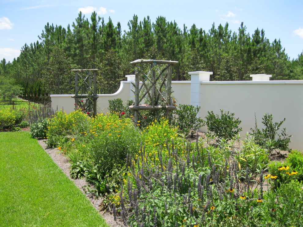 Diseño de jardín tradicional en patio trasero con jardín francés y exposición total al sol