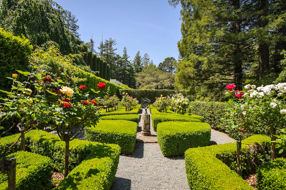 Cette image montre un grand jardin à la française arrière traditionnel l'été avec une exposition ensoleillée et du gravier.