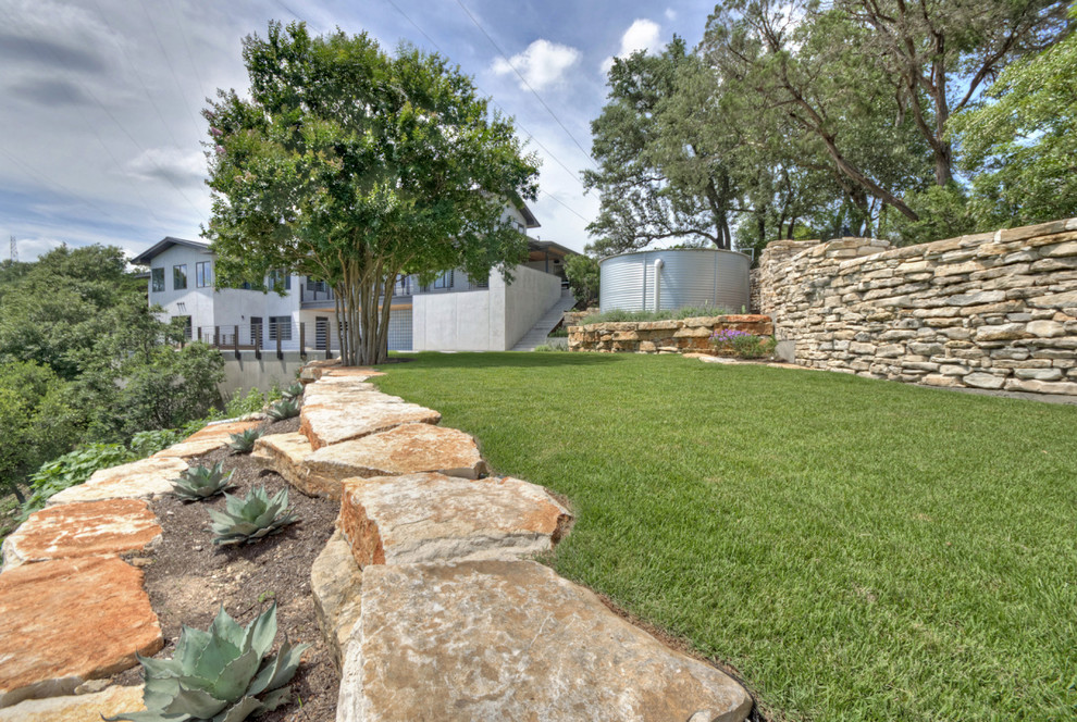 This is an example of a huge contemporary full sun backyard stone landscaping in Austin for spring.
