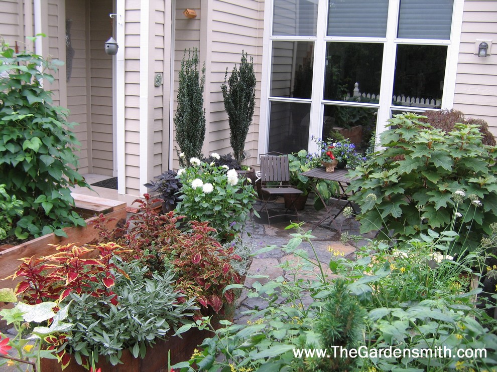 Photo of a small eclectic front garden in Portland with a potted garden and natural stone paving.