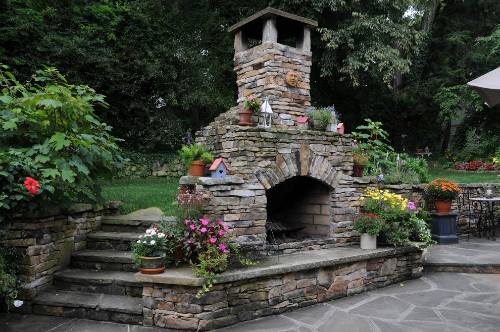 Aménagement d'un jardin arrière éclectique l'automne avec un foyer extérieur et des pavés en pierre naturelle.