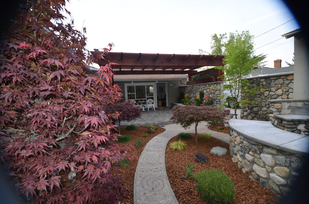 Foto di un piccolo giardino american style esposto a mezz'ombra dietro casa in primavera con un focolare e pavimentazioni in pietra naturale