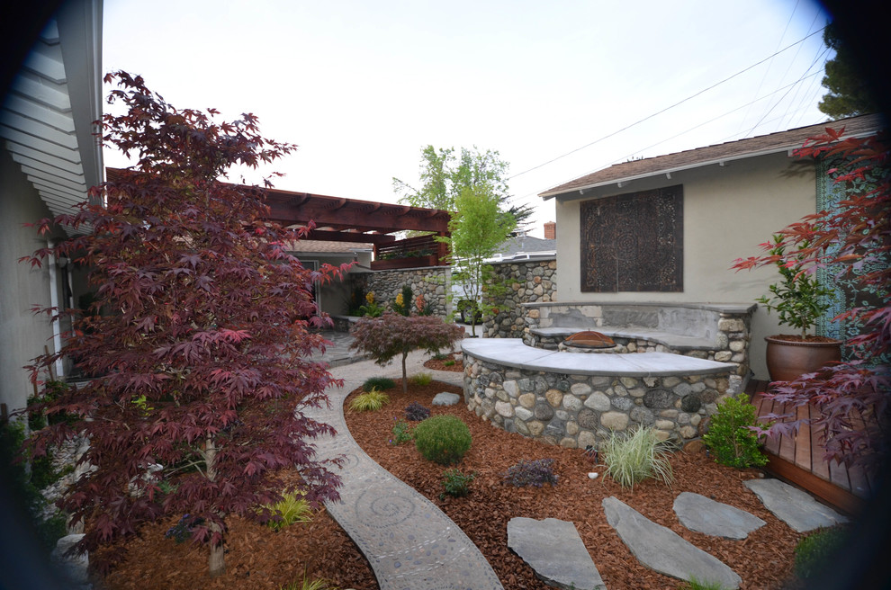 Kleiner, Halbschattiger Moderner Garten im Frühling, hinter dem Haus mit Feuerstelle und Natursteinplatten in Los Angeles