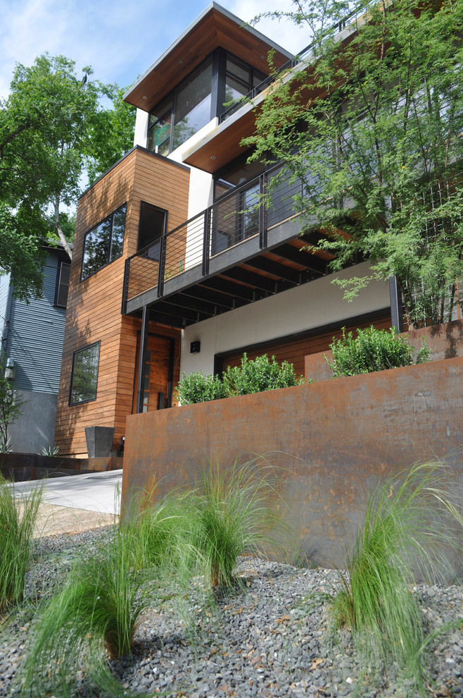 Photo of a large modern drought-tolerant and partial sun front yard gravel retaining wall landscape in Austin.
