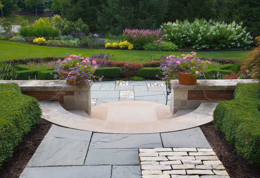 Immagine di un grande giardino classico esposto a mezz'ombra in estate con pavimentazioni in pietra naturale