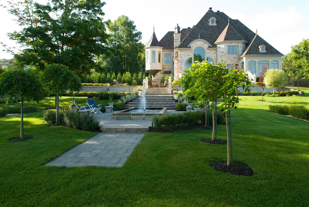 Cette image montre un jardin à la française arrière traditionnel avec une exposition partiellement ombragée et des pavés en béton.